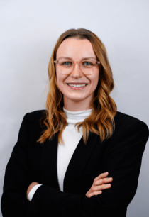 Porträtfoto eines weiblichen Teammitglieds mit Brille und langen Haaren.